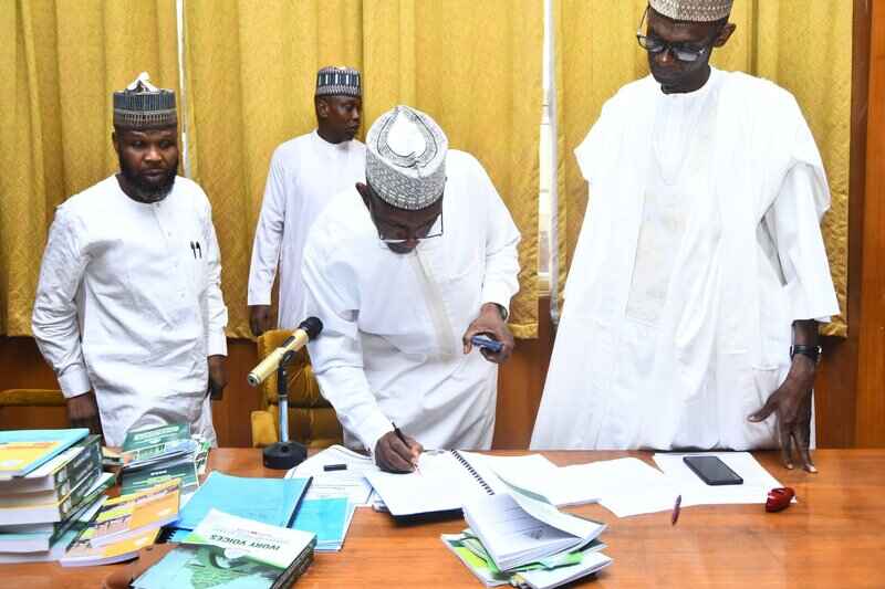 Outgoing VC, Prof. Kabiru Bala, signs the handing-over document as the new VC, Prof. Adamu Ahmed, looks on.