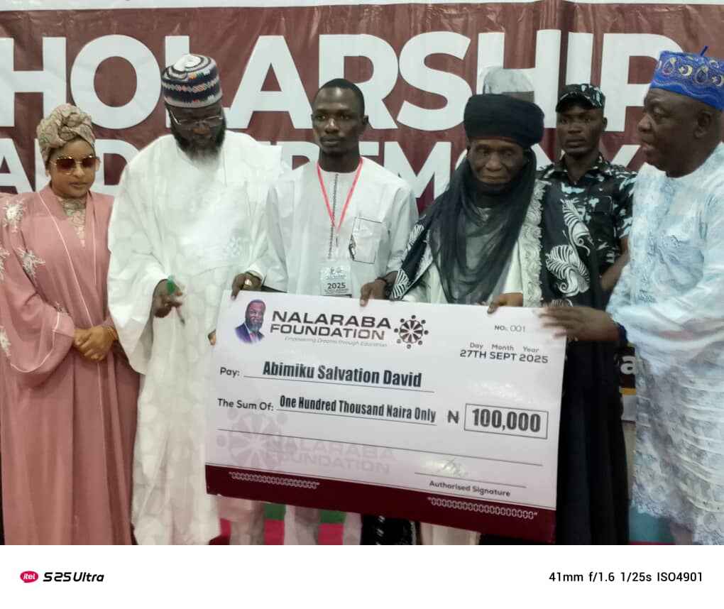 Photo shows Hon Abubakar Hassan Nalaraba presenting a scholarship cheque to a beneficiary in Nasarawa